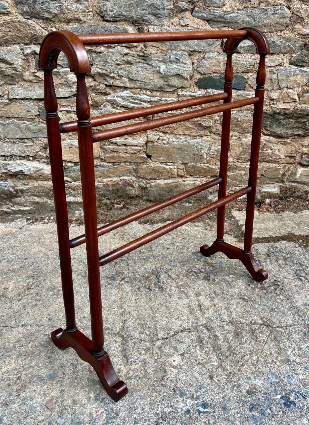 A freestanding Victorian mahogany towel rail featuring arched top cresting, turned upright supports, four horizontal bars, and shaped trestle feet. View III