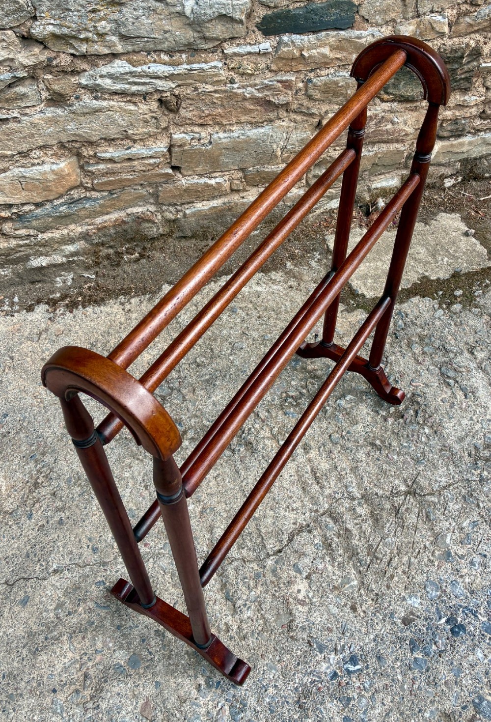 A freestanding Victorian mahogany towel rail featuring arched top cresting, turned upright supports, four horizontal bars, and shaped trestle feet. View IV
