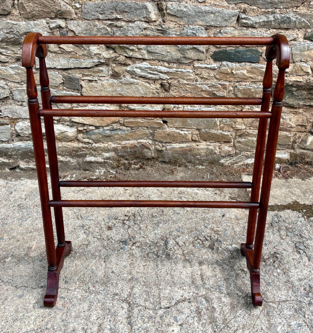 A freestanding Victorian mahogany towel rail featuring arched top cresting, turned upright supports, four horizontal bars, and shaped trestle feet. View VI