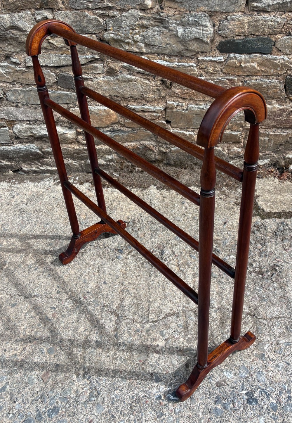 A freestanding Victorian mahogany towel rail featuring arched top cresting, turned upright supports, four horizontal bars, and shaped trestle feet. View IX