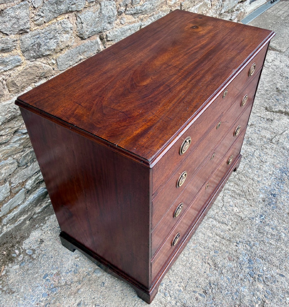 A Georgian mahogany chest of drawers featuring four graduated drawers with circular brass ring pull handles and bracket feet.