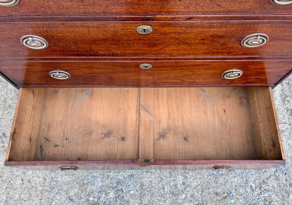 A Georgian mahogany chest of drawers featuring four graduated drawers with circular brass ring pull handles and bracket feet. View V