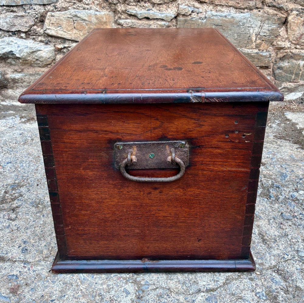 A rectangular warm brown teak storage chest featuring dovetailed corner joints and a central brass keyhole escutcheon. View X