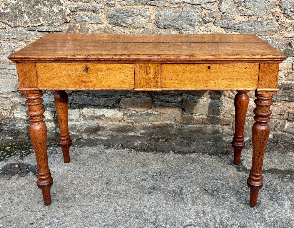 A Victorian golden oak console table featuring a rectangular top with a moulded edge, two frieze drawers, and four turned legs.