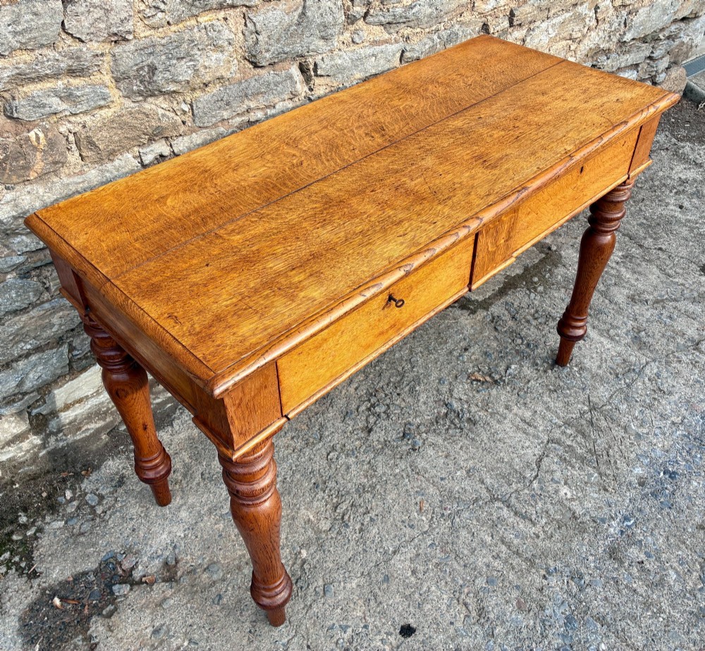 A Victorian golden oak console table featuring a rectangular top with a moulded edge, two frieze drawers, and four turned legs. View II