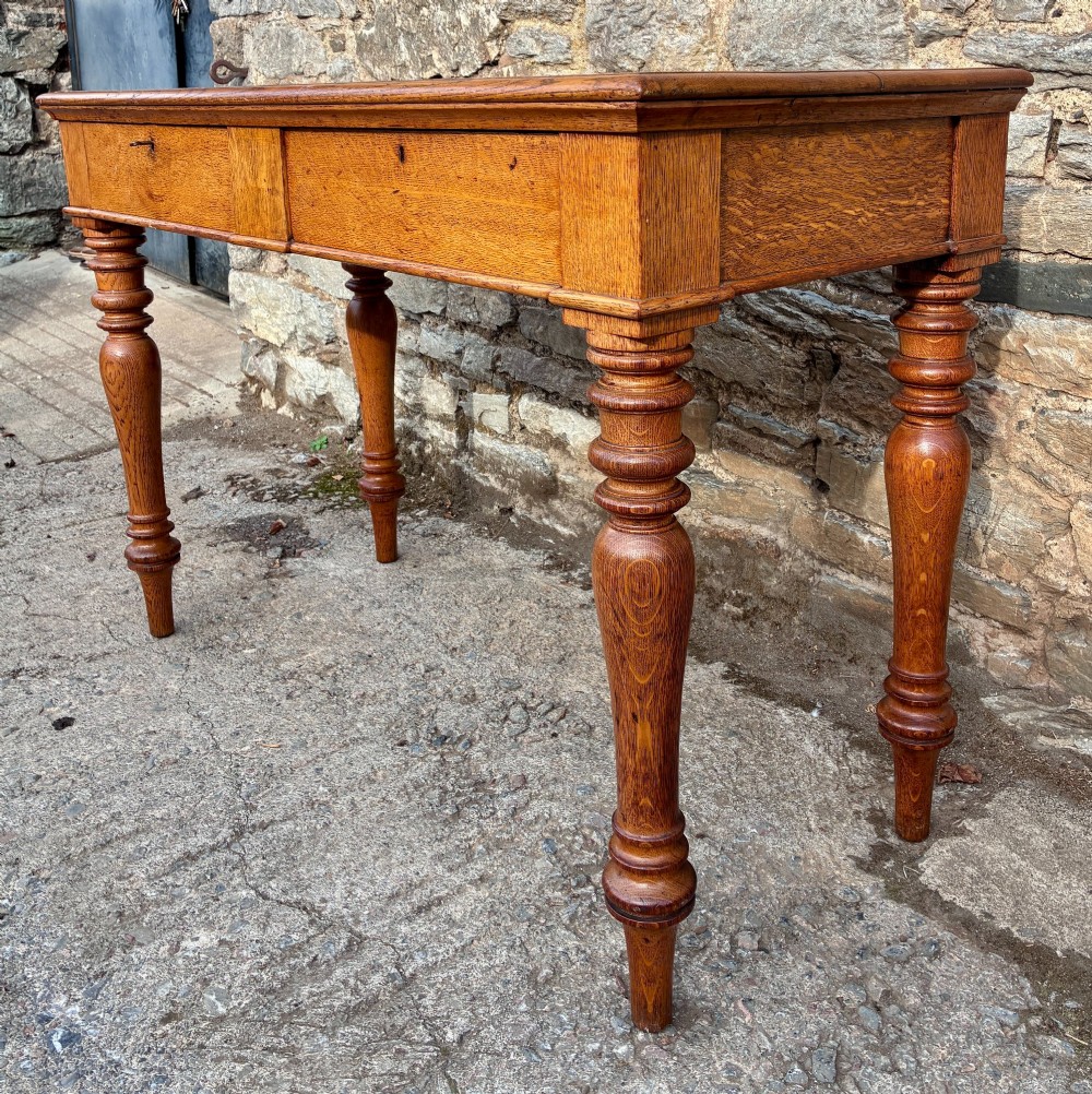 A Victorian golden oak console table featuring a rectangular top with a moulded edge, two frieze drawers, and four turned legs. View IX