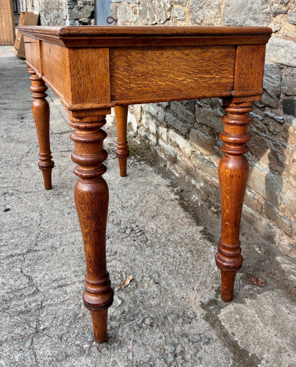 A Victorian golden oak console table featuring a rectangular top with a moulded edge, two frieze drawers, and four turned legs. View X