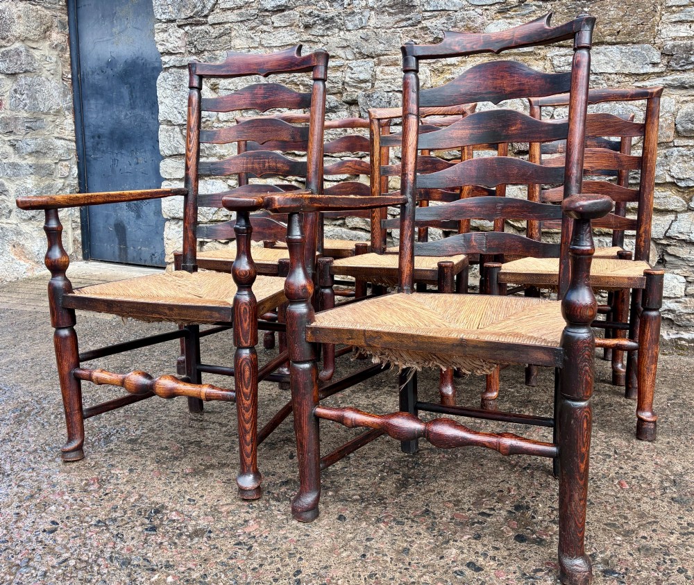 A set of eight 19th-century dark timber Lancashire ladderback dining chairs featuring wavy back slats, turned front stretchers, and woven rush seats, comprising two carver armchairs and six side chairs. View III