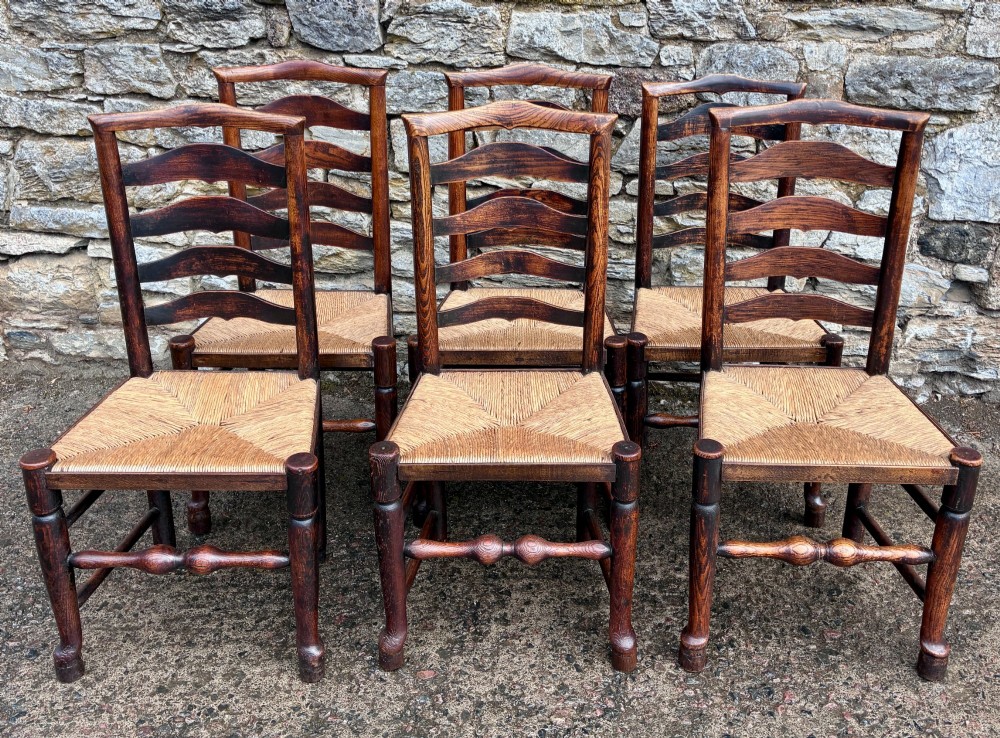 A set of eight 19th-century dark timber Lancashire ladderback dining chairs featuring wavy back slats, turned front stretchers, and woven rush seats, comprising two carver armchairs and six side chairs. View VII