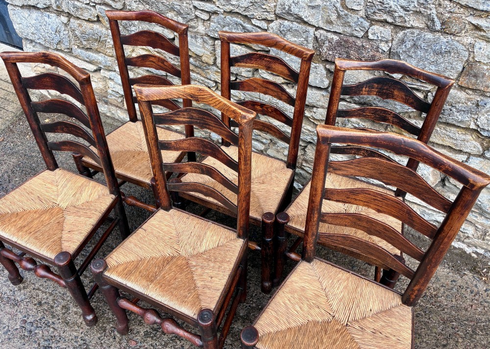 A set of eight 19th-century dark timber Lancashire ladderback dining chairs featuring wavy back slats, turned front stretchers, and woven rush seats, comprising two carver armchairs and six side chairs. View VIII