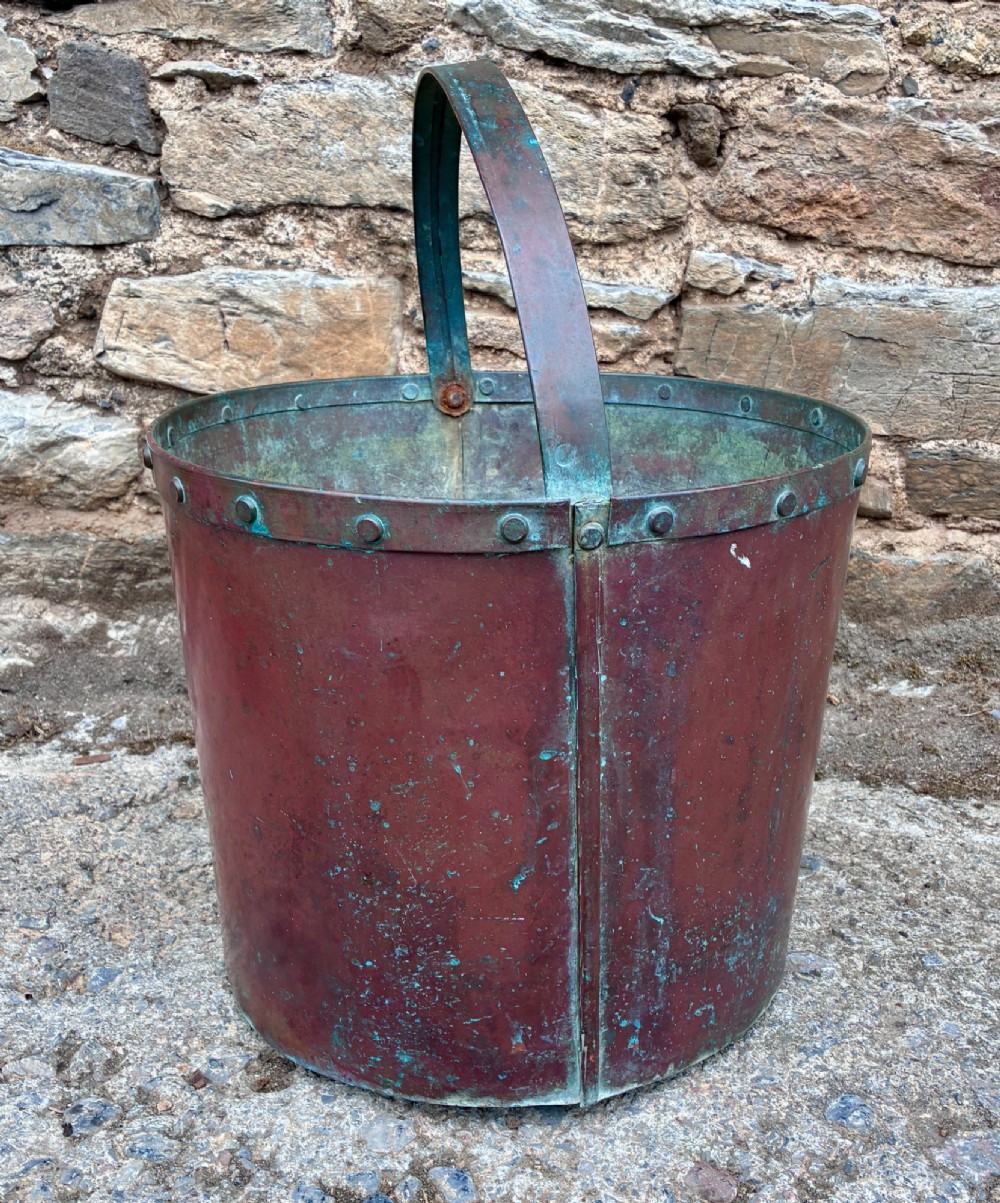 A cylindrical copper bucket featuring a riveted top band, a swing metal handle, and visible green verdigris patination. View II