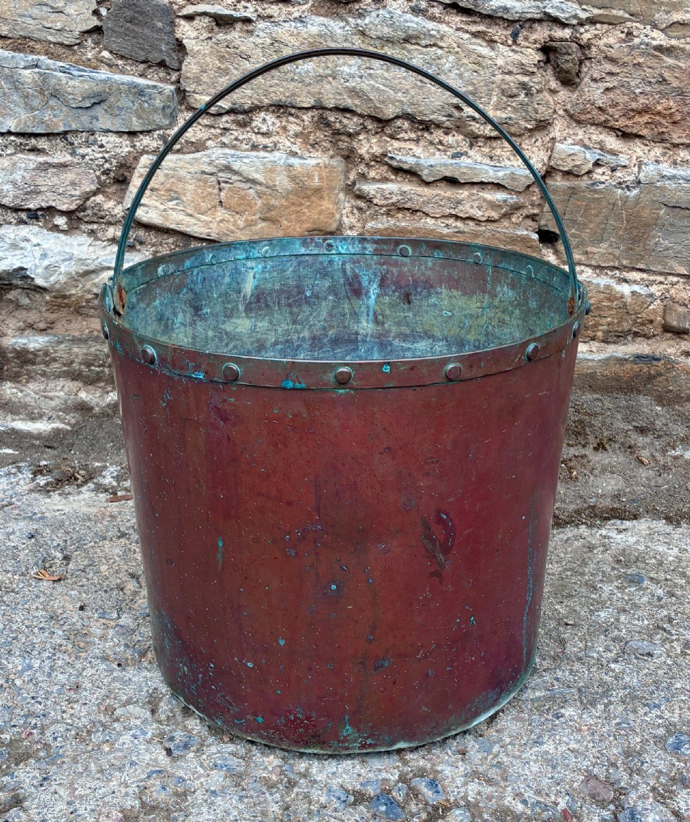 A cylindrical copper bucket featuring a riveted top band, a swing metal handle, and visible green verdigris patination. View IV