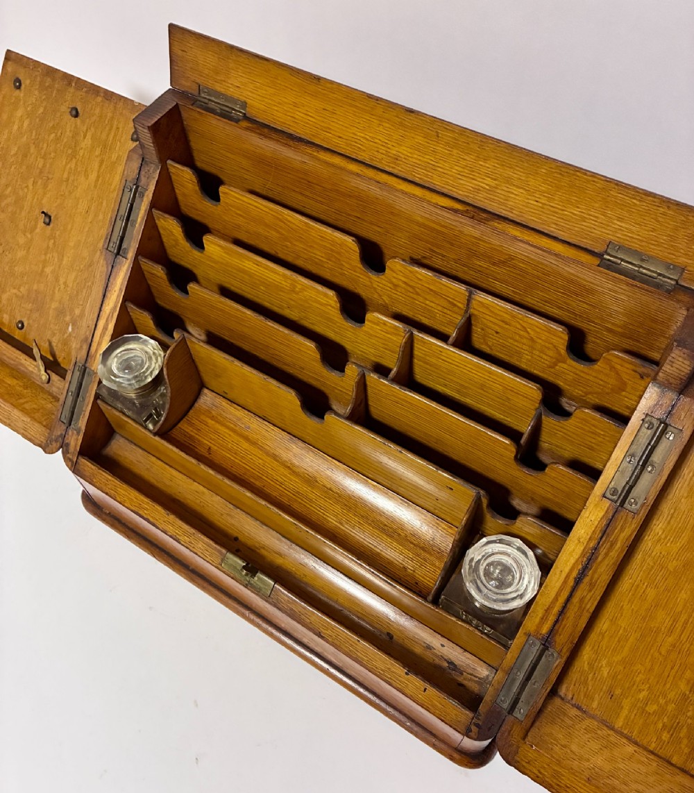 A Victorian oak stationery cabinet featuring sloped double doors, a metal escutcheon with a key, and a moulded plinth base. View III