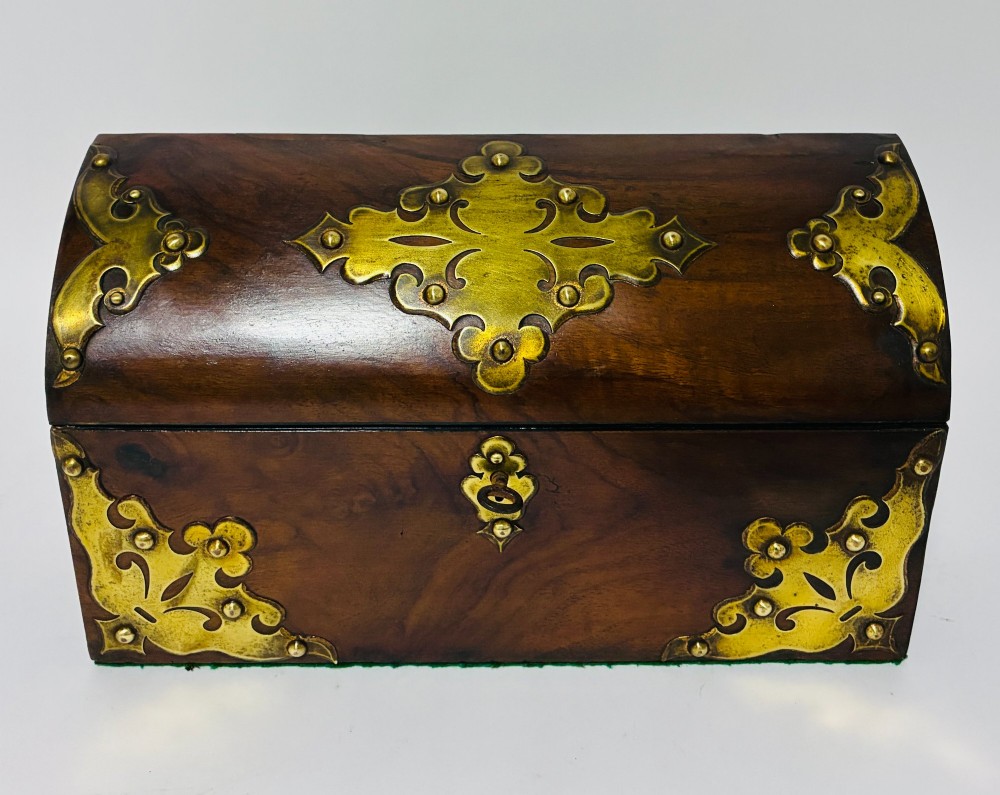A domed Victorian walnut box featuring decorative pierced brass corner mounts and a central brass keyhole.