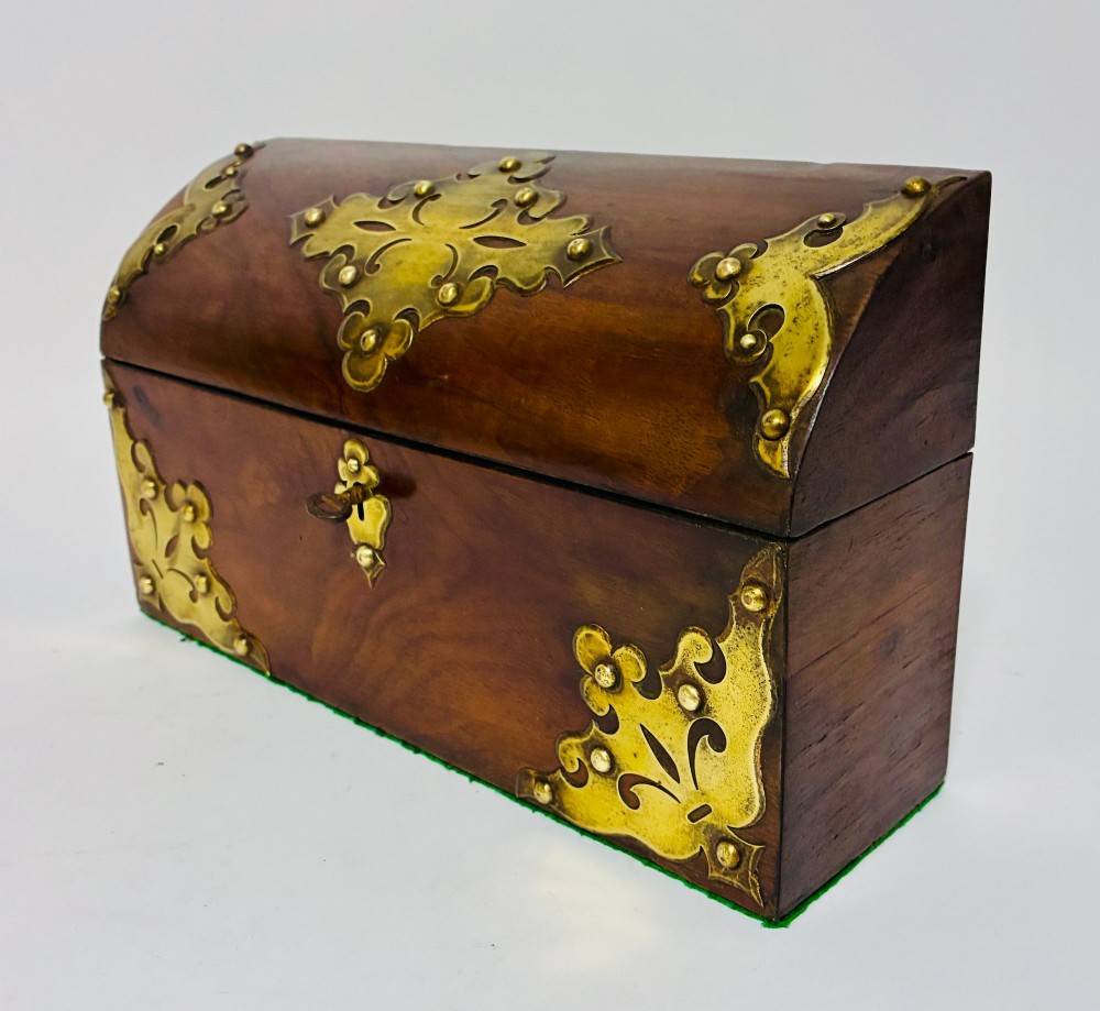 A domed Victorian walnut box featuring decorative pierced brass corner mounts and a central brass keyhole. View V
