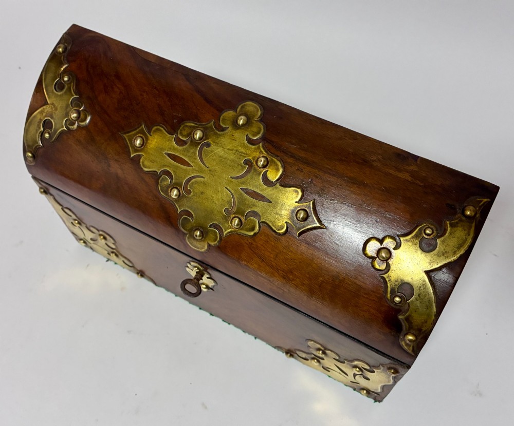 A domed Victorian walnut box featuring decorative pierced brass corner mounts and a central brass keyhole. View X