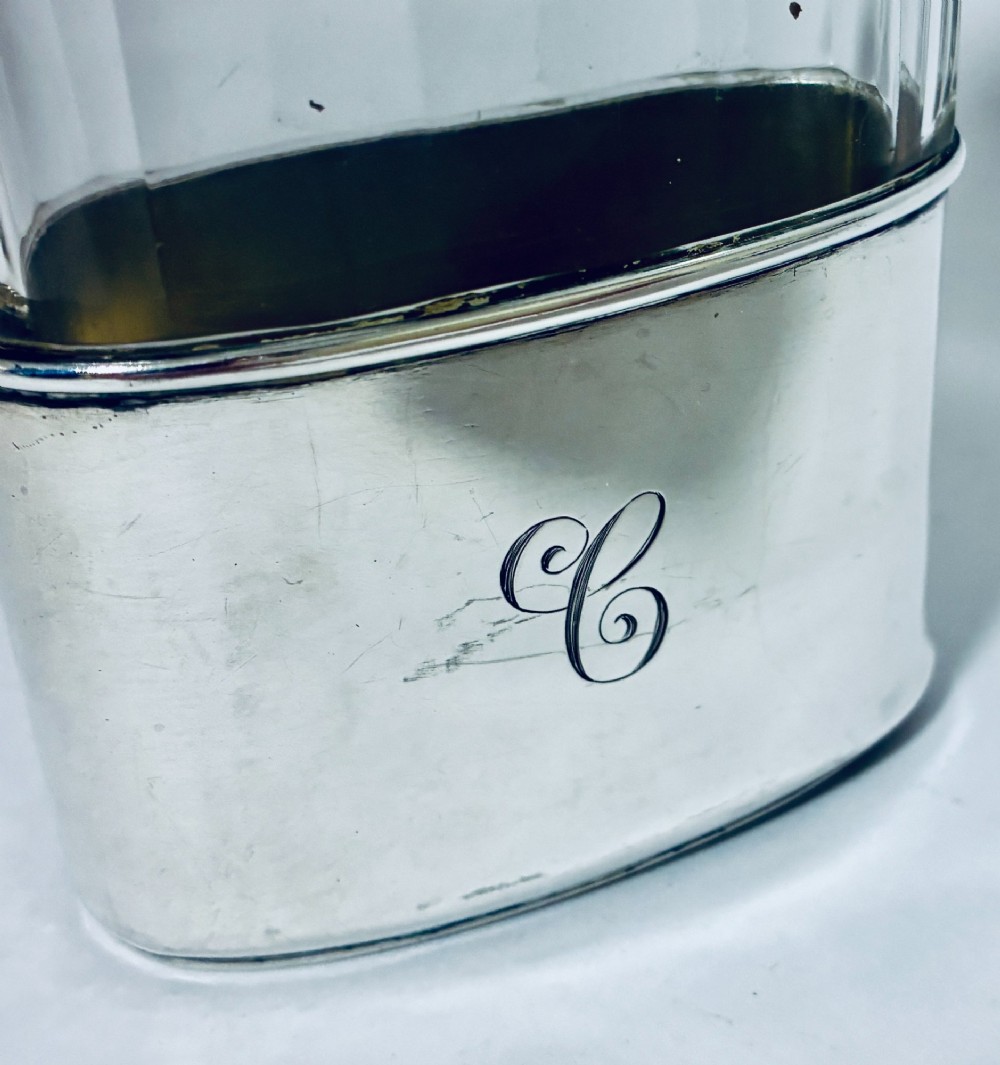 An antique cut-glass hip flask featuring a hallmarked sterling silver collar, chased cap, and a removable silver base cup engraved with the letter C. View VI