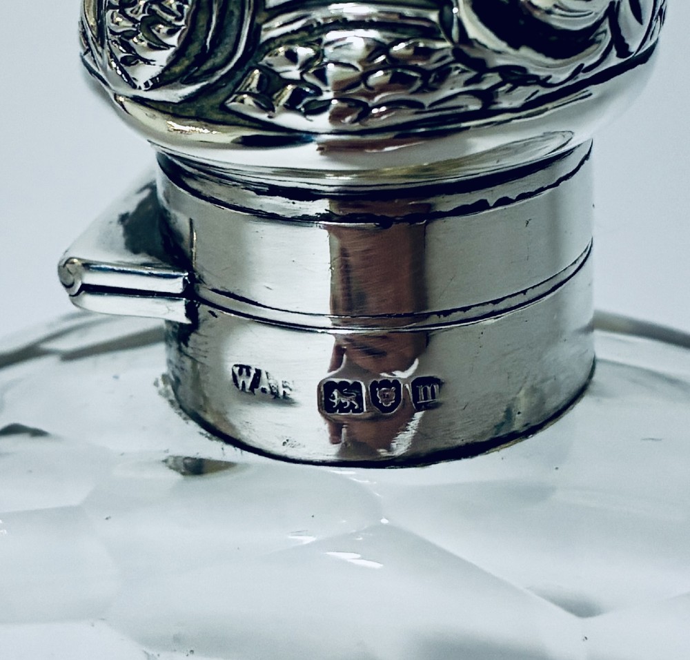 An antique cut-glass hip flask featuring a hallmarked sterling silver collar, chased cap, and a removable silver base cup engraved with the letter C. View VIII