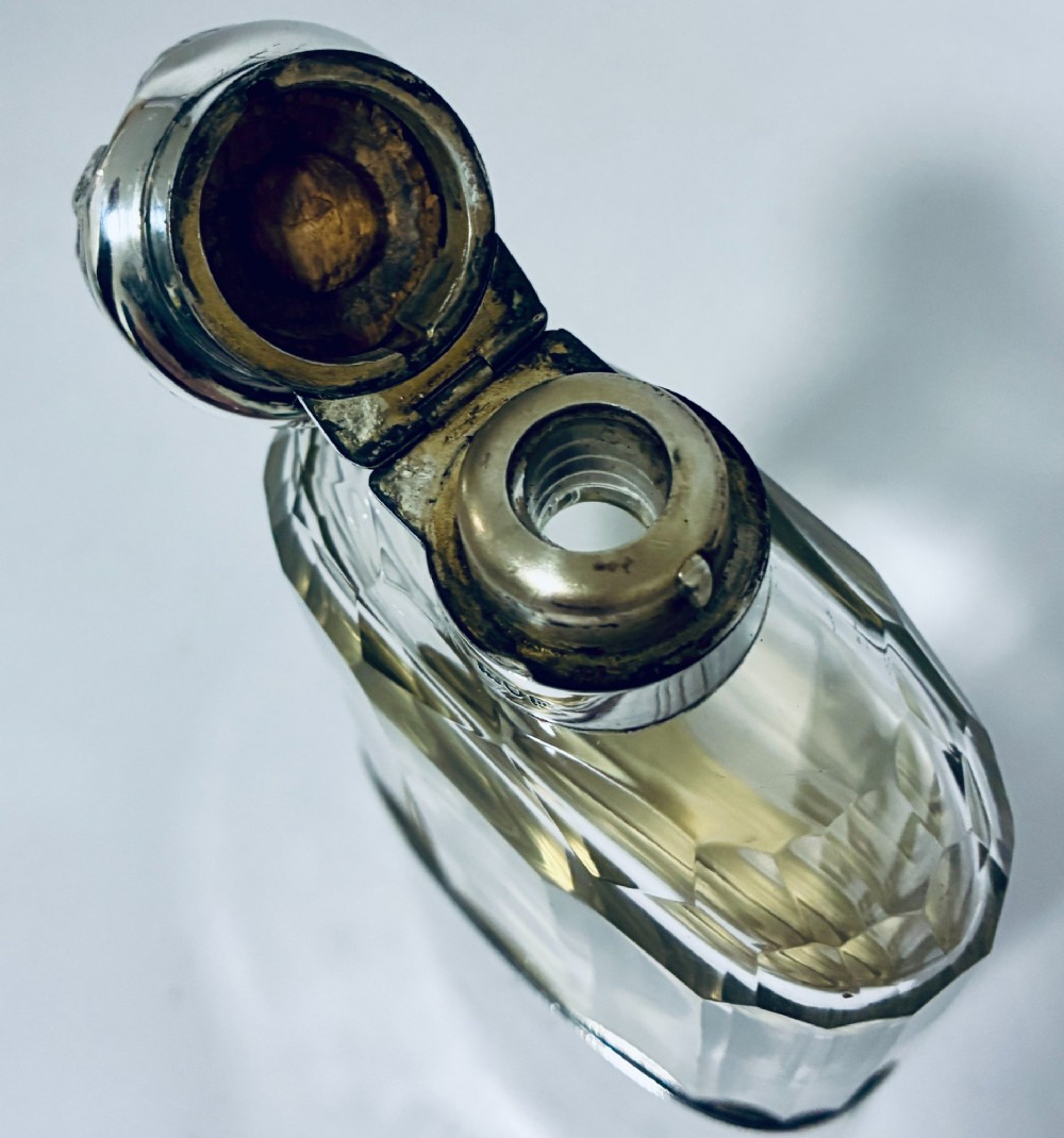 An antique cut-glass hip flask featuring a hallmarked sterling silver collar, chased cap, and a removable silver base cup engraved with the letter C. View XI