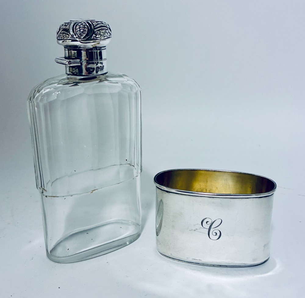 An antique cut-glass hip flask featuring a hallmarked sterling silver collar, chased cap, and a removable silver base cup engraved with the letter C. View XII
