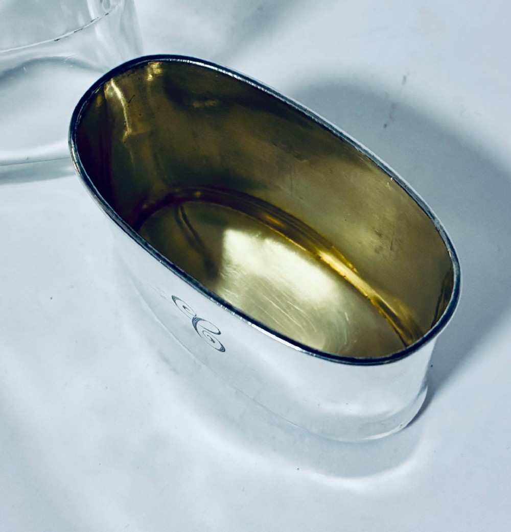 An antique cut-glass hip flask featuring a hallmarked sterling silver collar, chased cap, and a removable silver base cup engraved with the letter C. View XIII
