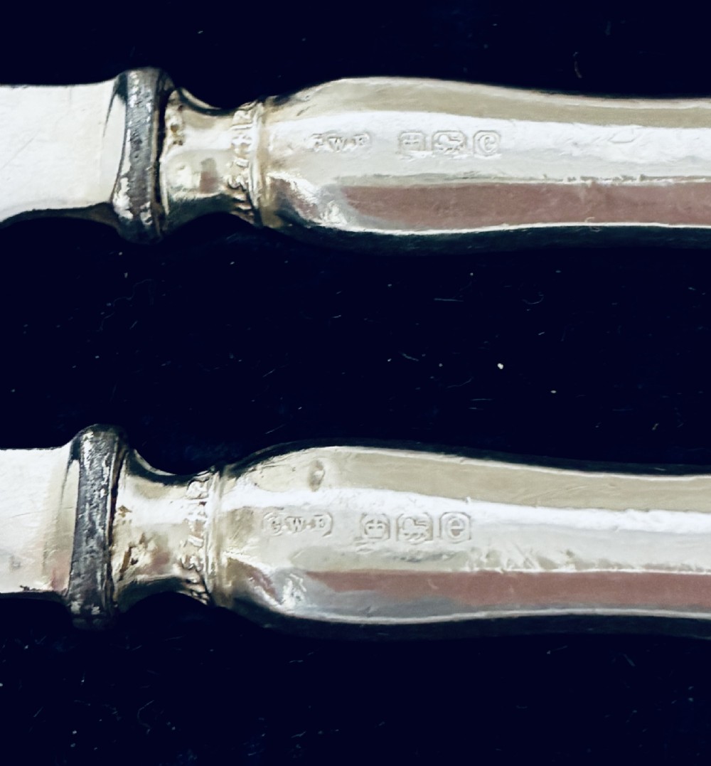 A set of six silver-handled butter knives presented in an open velvet- and silk-lined storage case. View VI