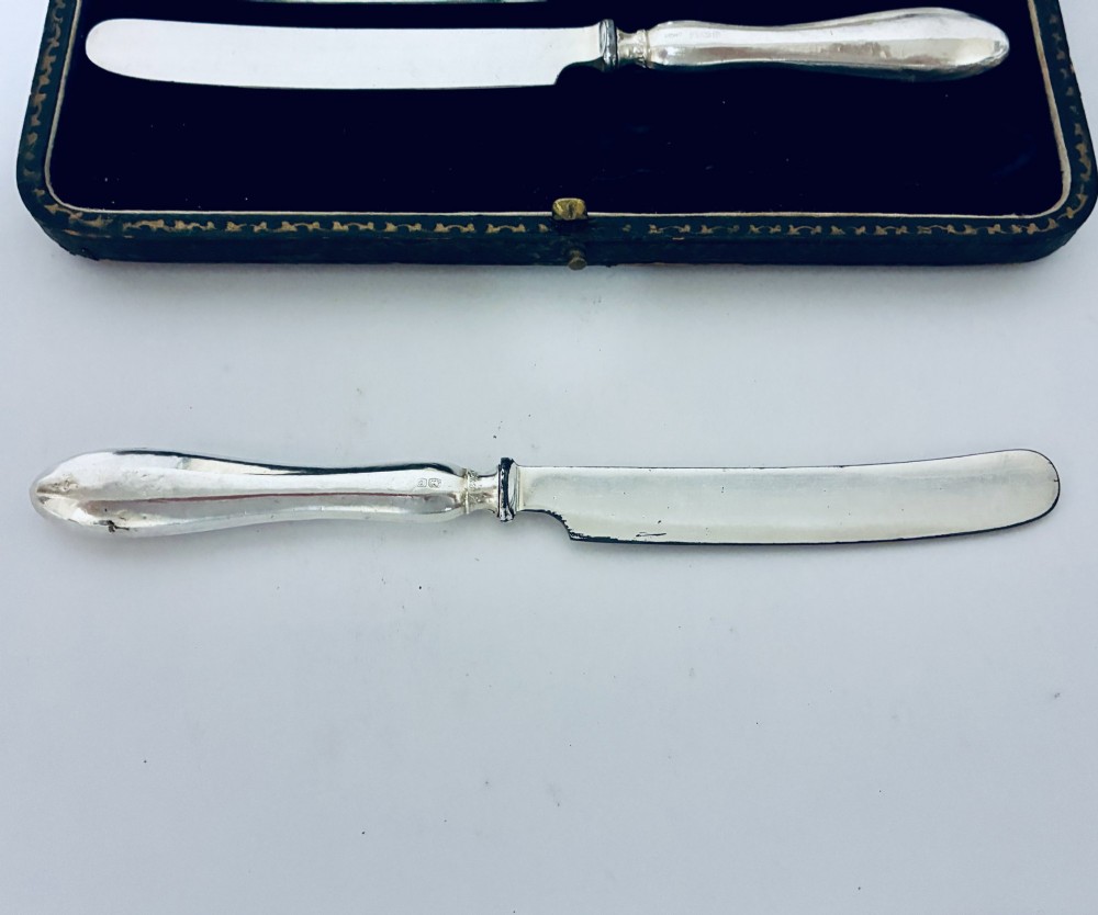 A set of six silver-handled butter knives presented in an open velvet- and silk-lined storage case. View VII