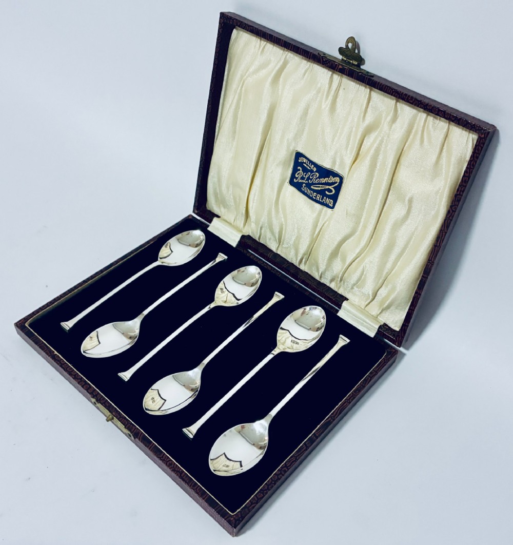 A set of six silver seal top spoons displayed inside a dark presentation box lined with cream satin and navy velvet. View II