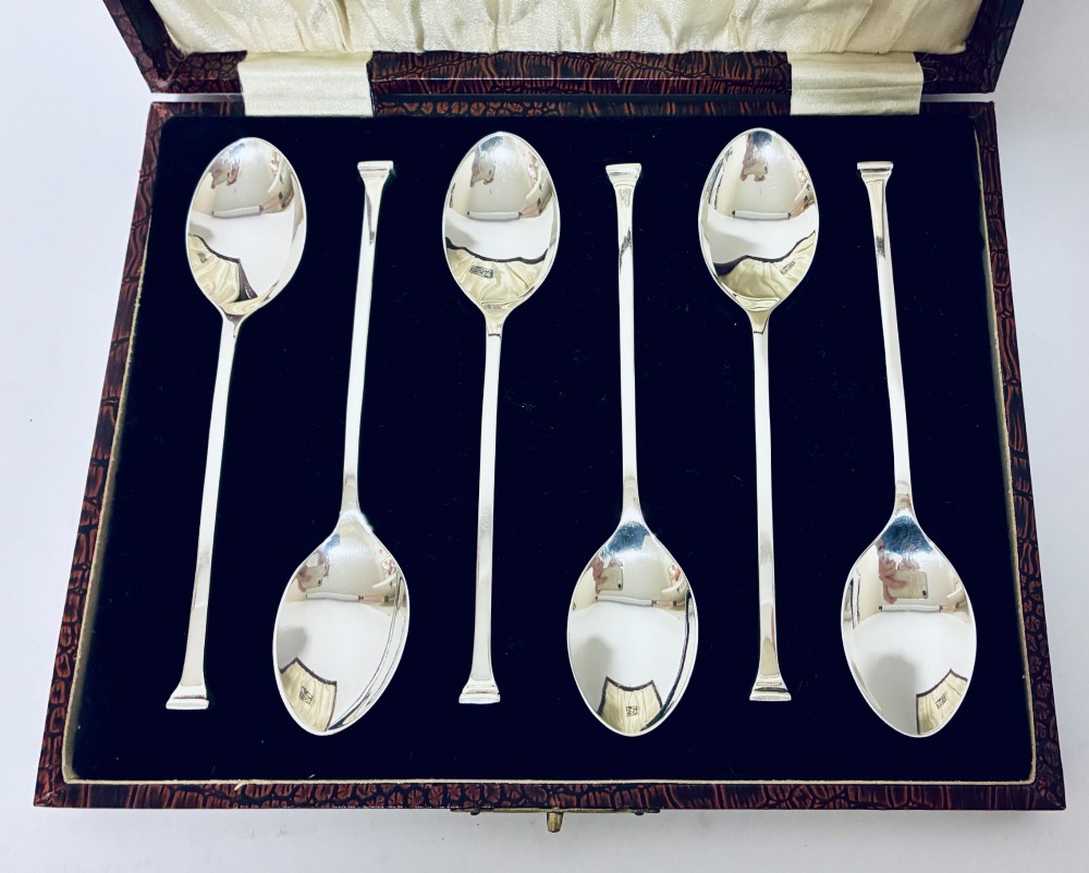 A set of six silver seal top spoons displayed inside a dark presentation box lined with cream satin and navy velvet. View III