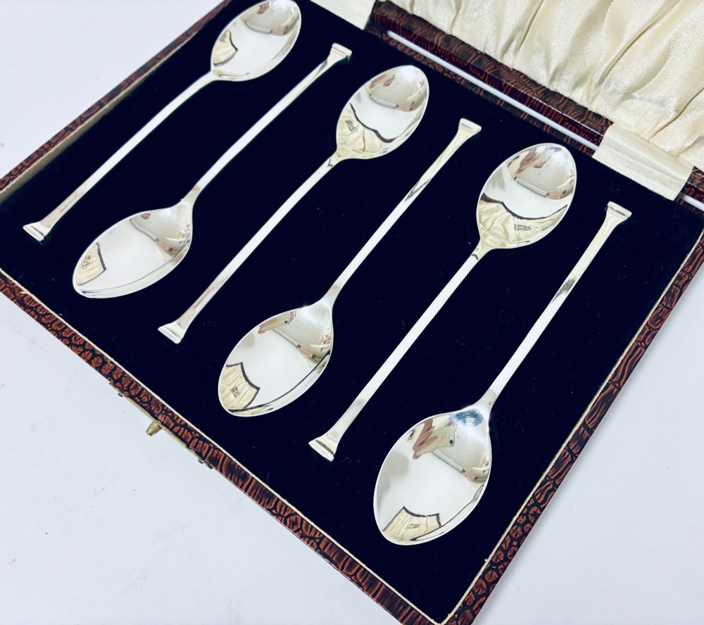 A set of six silver seal top spoons displayed inside a dark presentation box lined with cream satin and navy velvet. View IV
