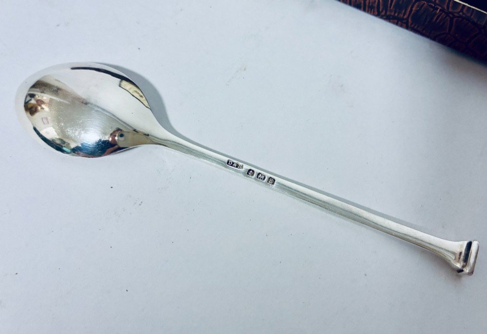A set of six silver seal top spoons displayed inside a dark presentation box lined with cream satin and navy velvet. View V