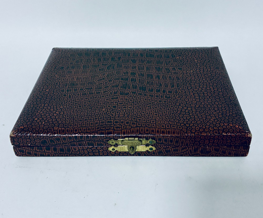 A set of six silver seal top spoons displayed inside a dark presentation box lined with cream satin and navy velvet. View VII