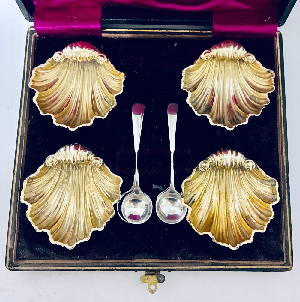 A cased set of four Victorian shell-shaped silver salt cellars with gilded interiors and two matching silver spoons in a velvet-lined box. View II