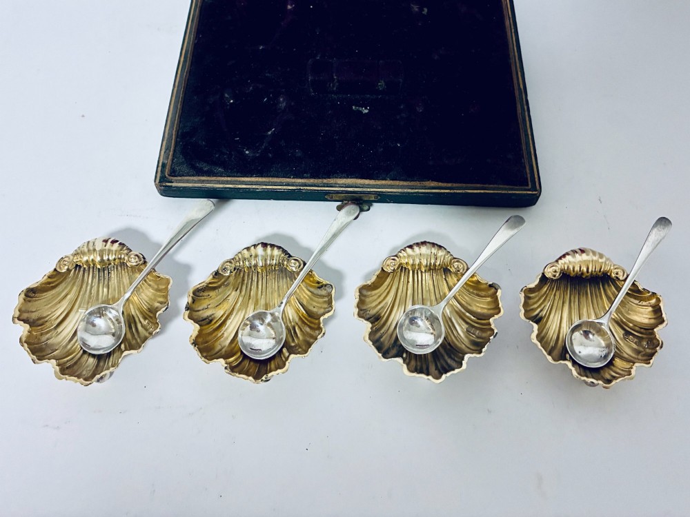 A cased set of four Victorian shell-shaped silver salt cellars with gilded interiors and two matching silver spoons in a velvet-lined box. View III