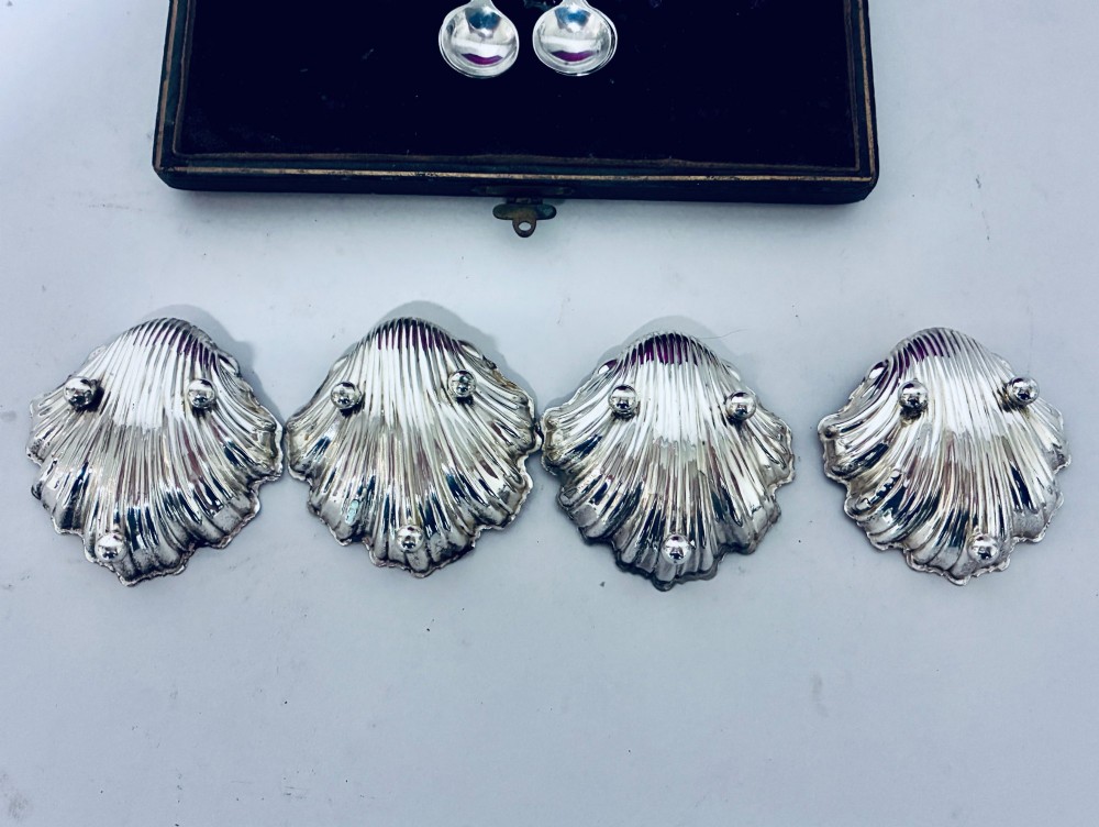 A cased set of four Victorian shell-shaped silver salt cellars with gilded interiors and two matching silver spoons in a velvet-lined box. View VI