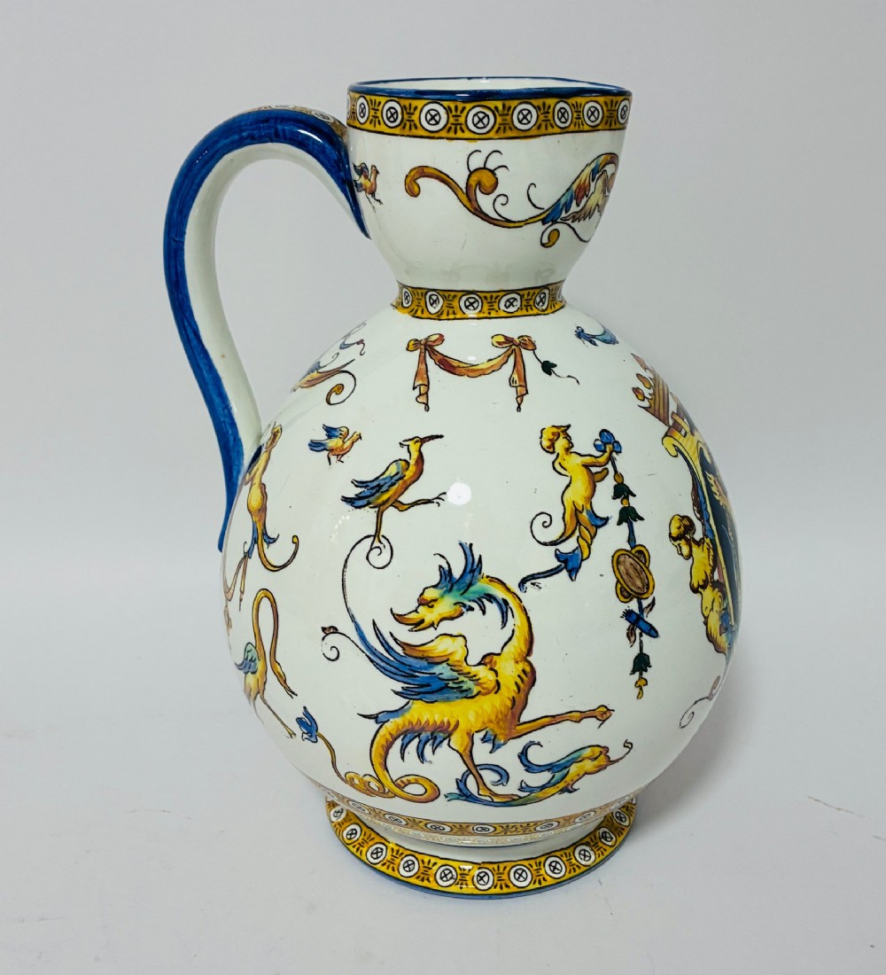 A white tin-glazed earthenware ewer decorated with hand-painted Renaissance grotesque figures, a central crest, and a blue handle. View III