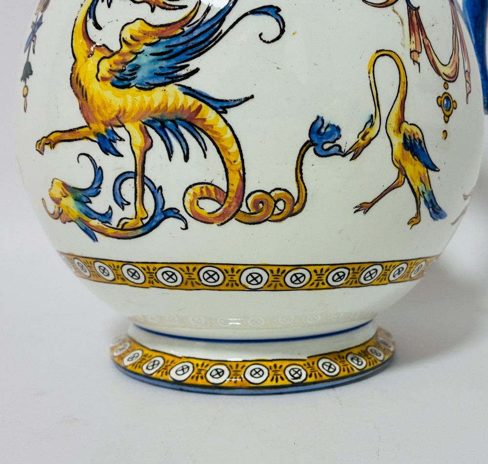A white tin-glazed earthenware ewer decorated with hand-painted Renaissance grotesque figures, a central crest, and a blue handle. View VIII