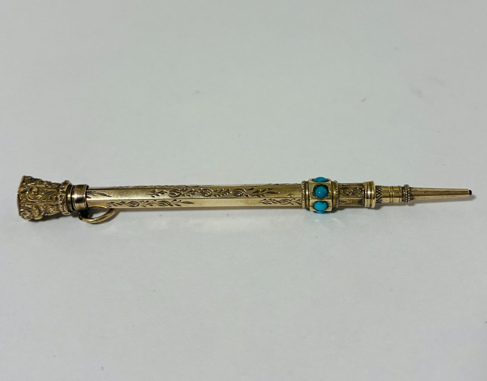An ornate Victorian gold propelling pencil featuring engraved floral motifs, set with round turquoise cabochons and fitted with a suspension ring. View IV