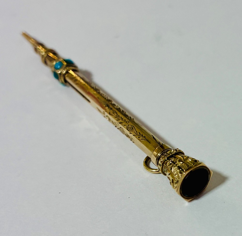 An ornate Victorian gold propelling pencil featuring engraved floral motifs, set with round turquoise cabochons and fitted with a suspension ring. View VII