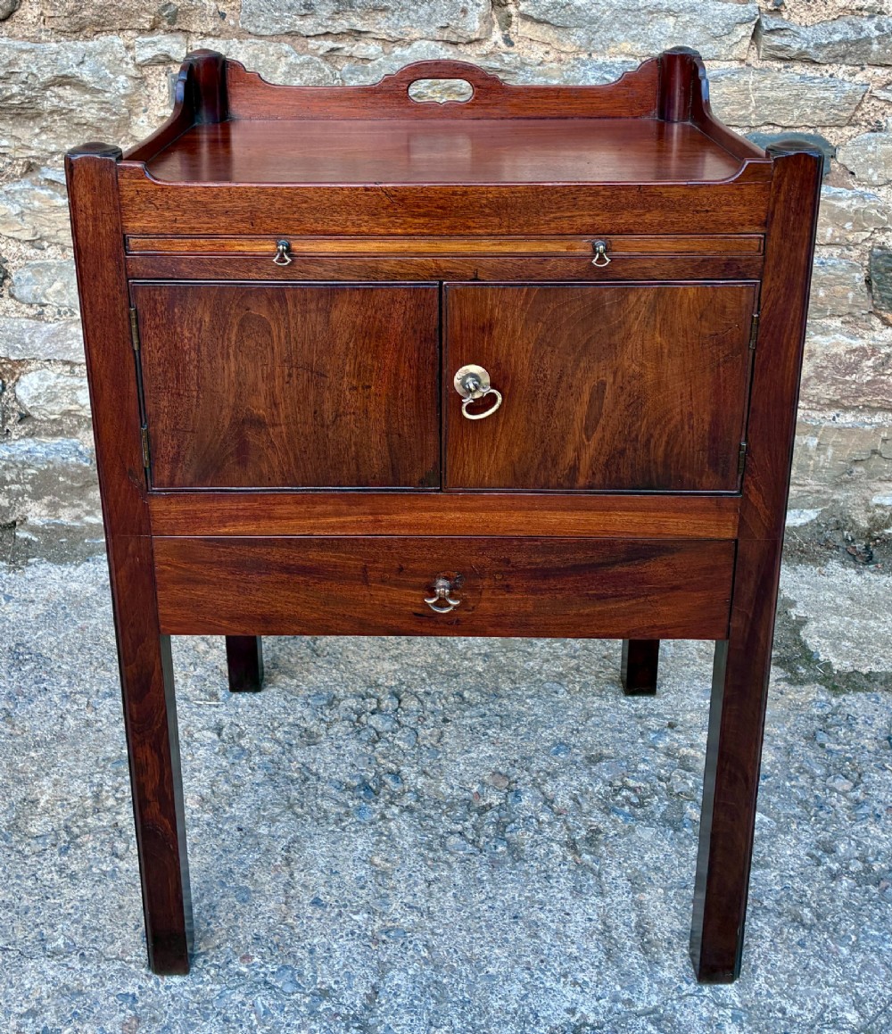 A Georgian mahogany tray top commode featuring a gallery top with pierced carrying handles, double cupboard doors, and a lower drawer on square legs. View II