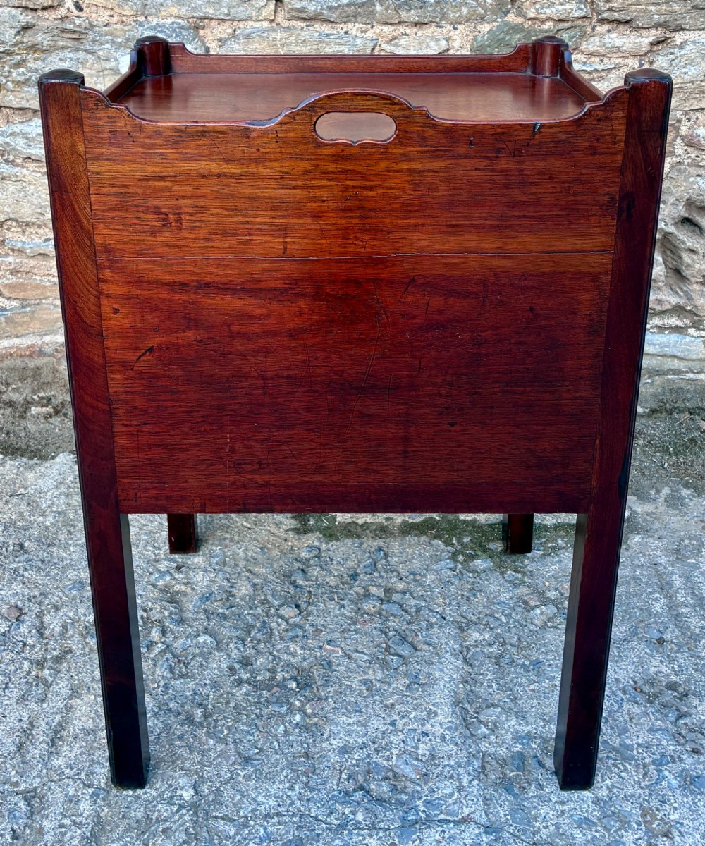 A Georgian mahogany tray top commode featuring a gallery top with pierced carrying handles, double cupboard doors, and a lower drawer on square legs. View X