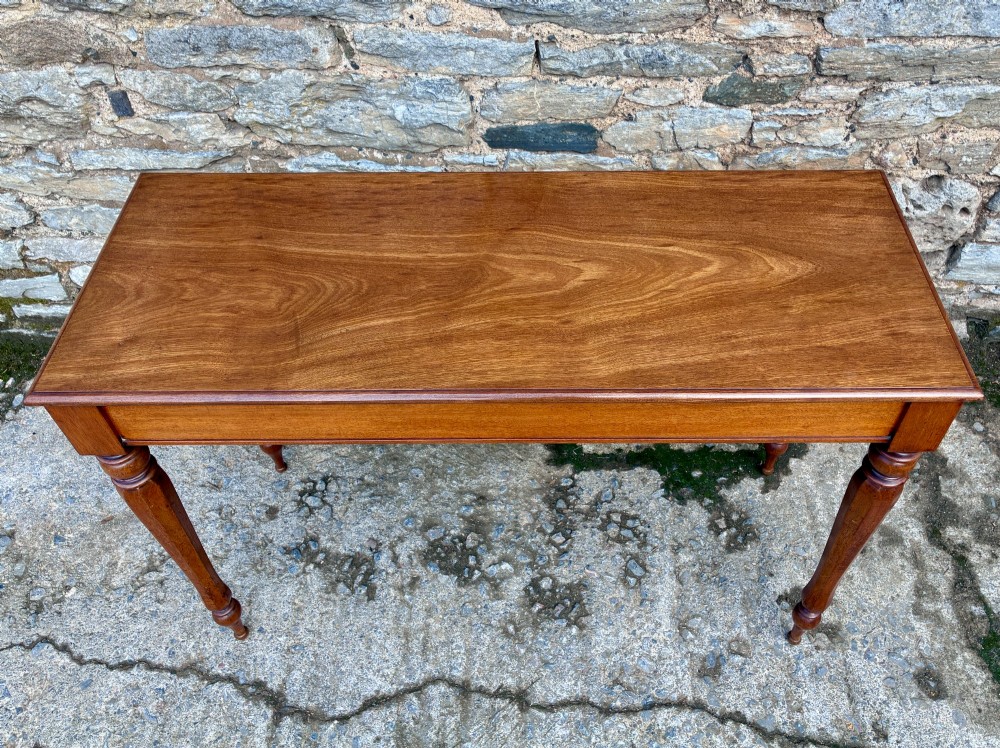 A rectangular Victorian mahogany console table featuring a smooth polished top surface, straight apron, and four turned legs. View II