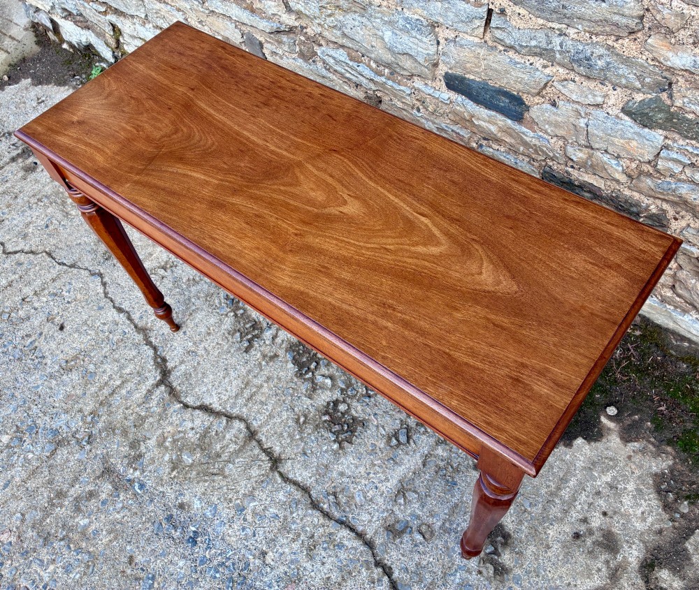 A rectangular Victorian mahogany console table featuring a smooth polished top surface, straight apron, and four turned legs. View III