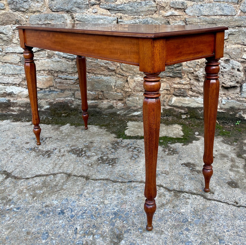 A rectangular Victorian mahogany console table featuring a smooth polished top surface, straight apron, and four turned legs. View IV