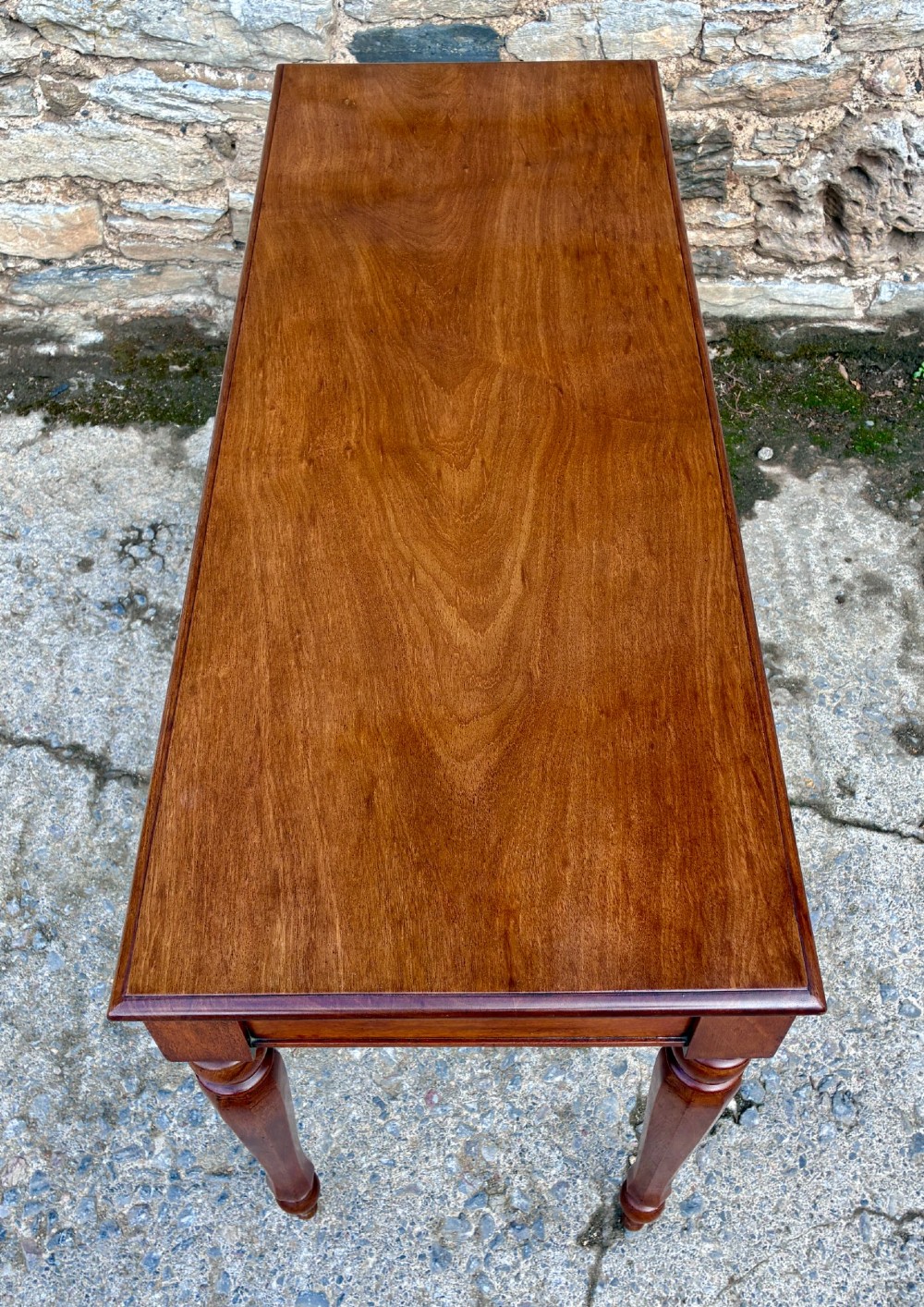 A rectangular Victorian mahogany console table featuring a smooth polished top surface, straight apron, and four turned legs. View VI