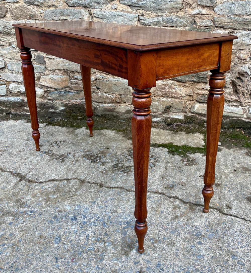A rectangular Victorian mahogany console table featuring a smooth polished top surface, straight apron, and four turned legs. View VIII