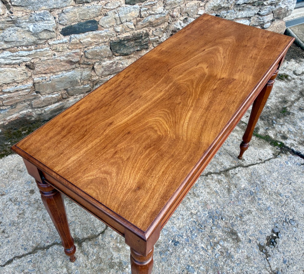 A rectangular Victorian mahogany console table featuring a smooth polished top surface, straight apron, and four turned legs. View X