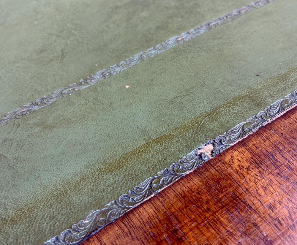 A Victorian mahogany writing table featuring a green leather top, two front drawers with turned wooden knobs, and fluted turned legs on brass castors. View X