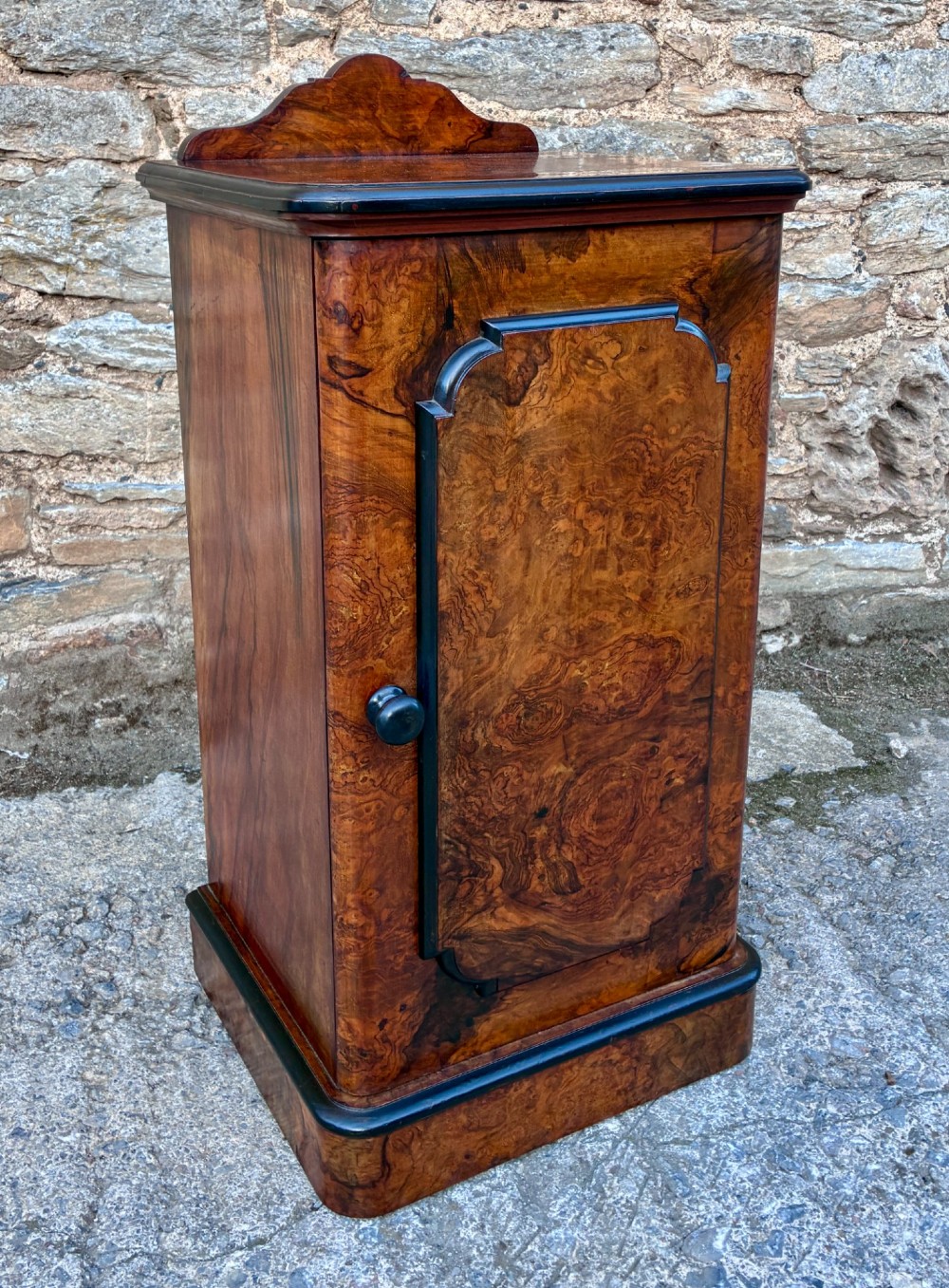 A Victorian burr walnut pot cupboard featuring a single door with ebonised moulding, a rounded top edge, shaped splashback gallery, and dark wooden knob. View X