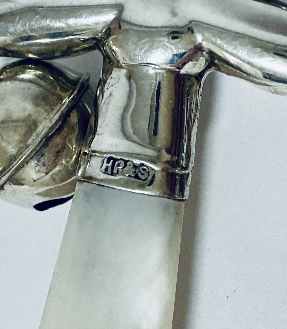 An antique sterling silver baby rattle shaped like a jester with hanging bells, a mother-of-pearl handle, and an attached ring. View VIII